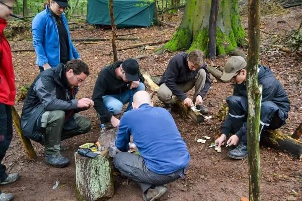 Gruppe arbeitet an einem Holzstück, um Zunder vorzubereiten