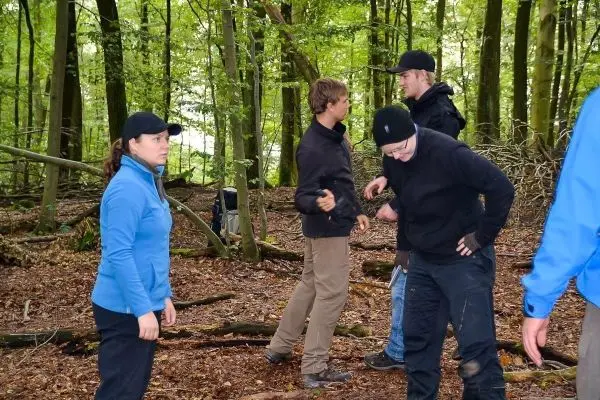 Gruppe von Personen in einem Wald, die sich unterhalten und bewegen