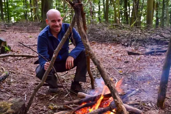 Kleine Flamme brennt zwischen Holzscheiten im Wald
