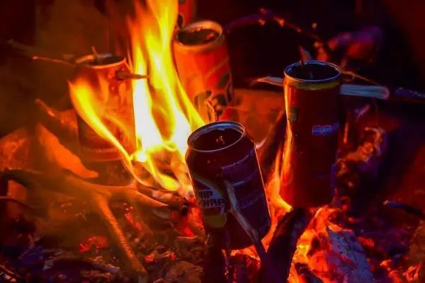 Kleine Flamme umgibt mehrere Dosen auf einem Holzstapel