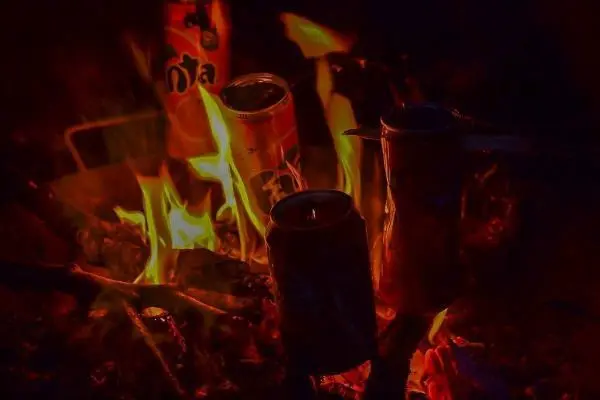 Kleine Flamme umgibt mehrere Dosen im Feuer