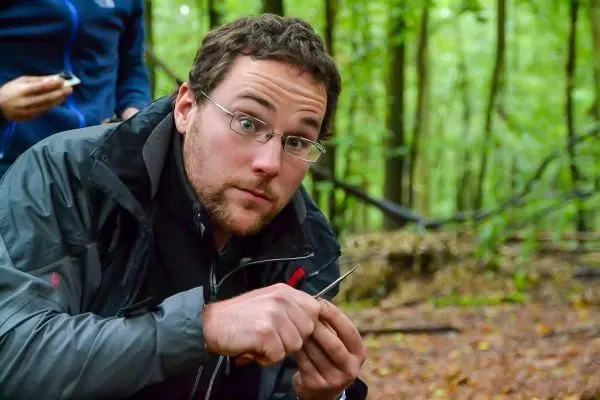 Mann bearbeitet ein kleines Werkzeug im Wald