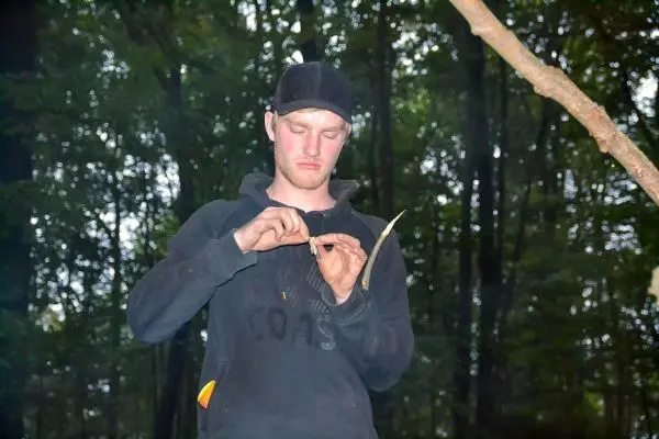 Mann bearbeitet einen Holzstock mit einem Messer im Wald