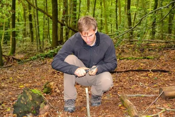 Messer bearbeitet Holzstück auf dem Waldboden