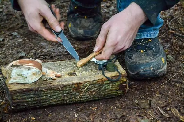 Messer schneidet Holzstück auf einem Baumstamm im Wald