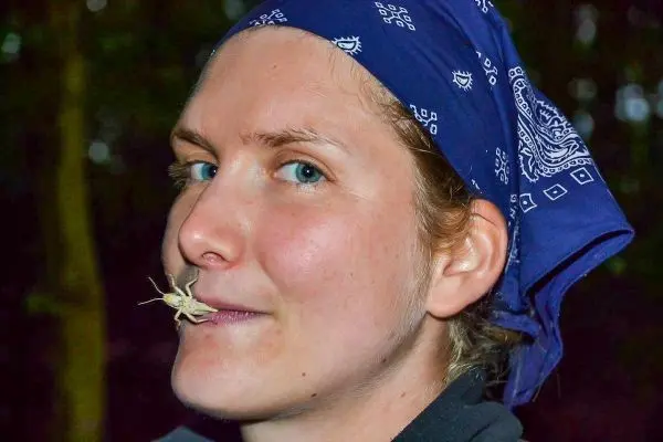 Person hält ein Insekt zwischen den Lippen