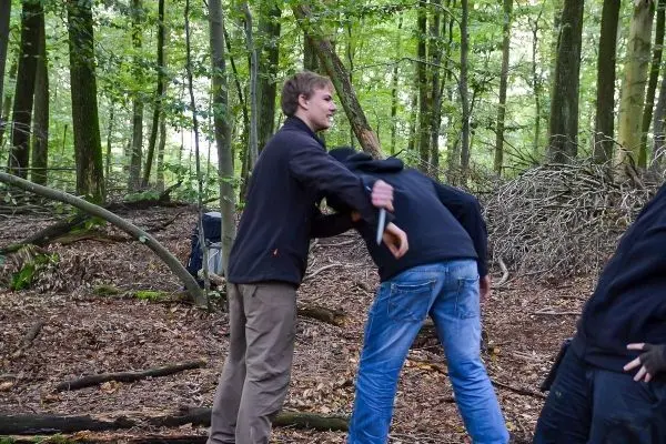 Person hilft anderer Person beim Üben einer Technik im Wald