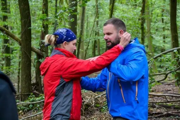 Person zeigt einer anderen Person eine Technik im Wald