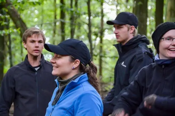 Vier Personen stehen in einem Wald und unterhalten sich