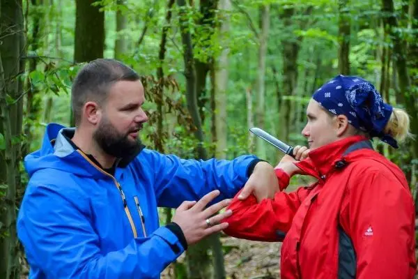 Zwei Personen demonstrieren eine Selbstverteidigungstechnik im Wald