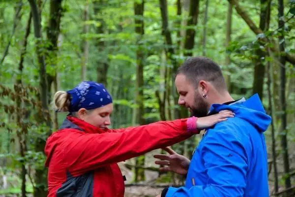 Zwei Personen in Outdoor-Bekleidung üben eine Technik im Wald