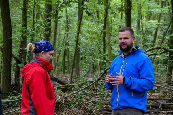 Zwei Personen stehen im Wald und unterhalten sich