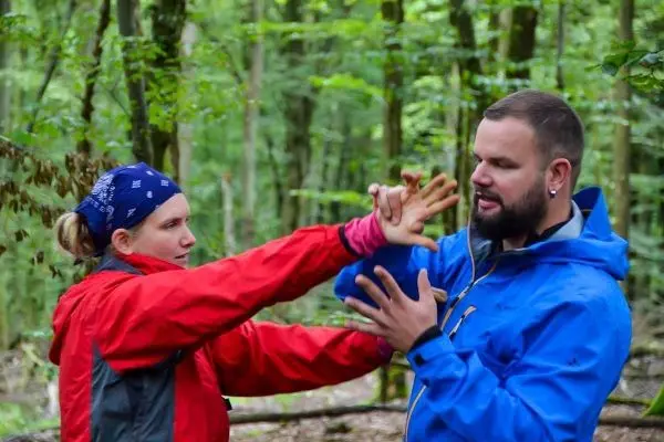 Zwei Personen üben eine Selbstverteidigungstechnik im Wald