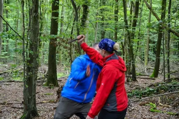 Zwei Personen üben eine Selbstverteidigungstechnik im Wald mit einem Messer