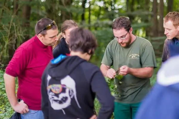 Eine Gruppe von Personen beobachtet einen Mann, der Pflanzenblätter in der Natur zeigt
