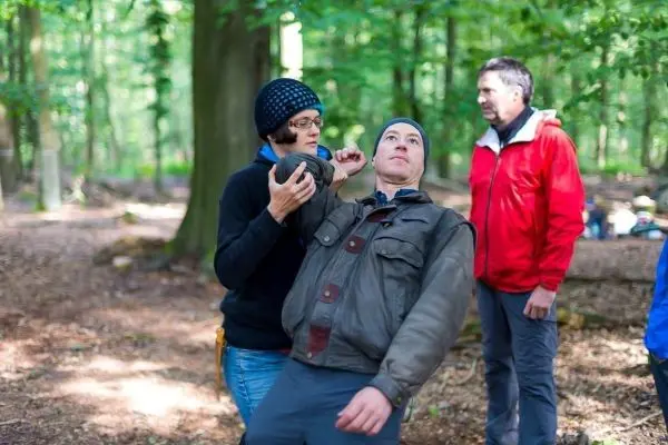 Eine Person führt eine Erste-Hilfe-Maßnahme bei einer anderen Person im Wald durch