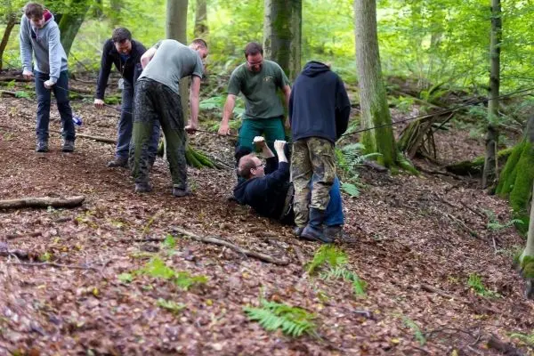 Gruppe hilft Person, die am Boden liegt, im Wald