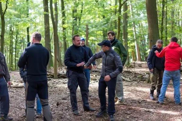 Gruppe von Personen steht im Wald und unterhält sich aktiv