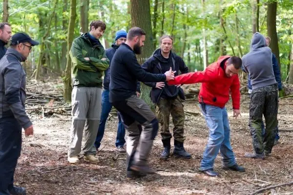 Gruppentraining im Wald, eine Person demonstriert eine Technik zur Selbstverteidigung