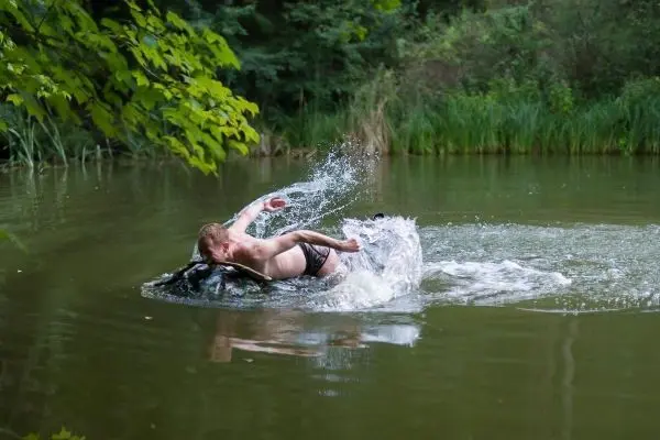 Junge springt ins Wasser und spritzt dabei Wasser auf