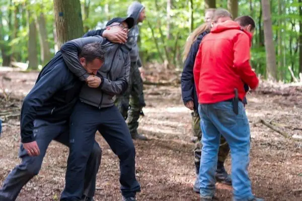 Kampftraining mit mehreren Personen im Wald, eine Person wird festgehalten