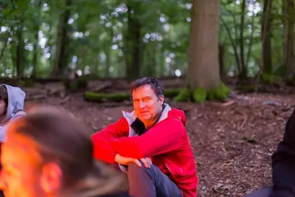 Kleines Bodenfeuer in einem Wald, Personen sitzen im Hintergrund