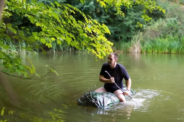 Mann paddelt auf improvisiertem Boot durch ruhiges Wasser