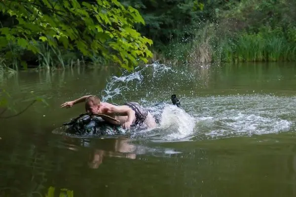 Mann schwimmt auf einem auf dem Wasser treibenden Objekt und spritzt Wasser