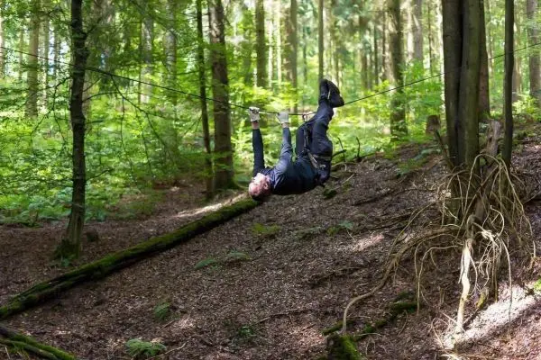 Mann überquert selbstgebaute Seilbrücke in einem Waldgebiet