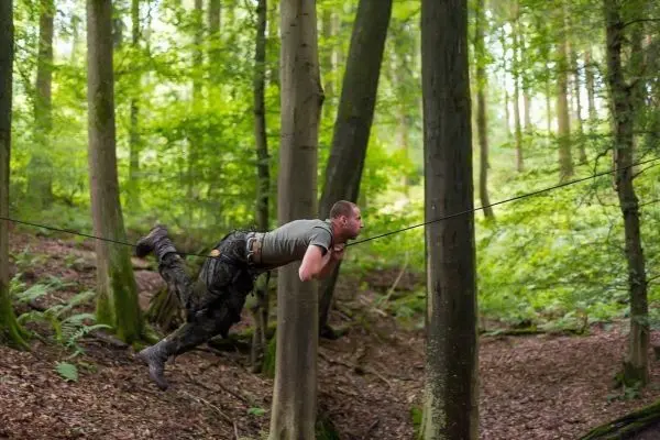 Mann überquert selbstgebaute Seilbrücke zwischen zwei Bäumen
