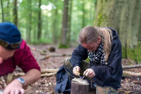 Messer bearbeitet Holzstück auf einem Baumstumpf im Wald