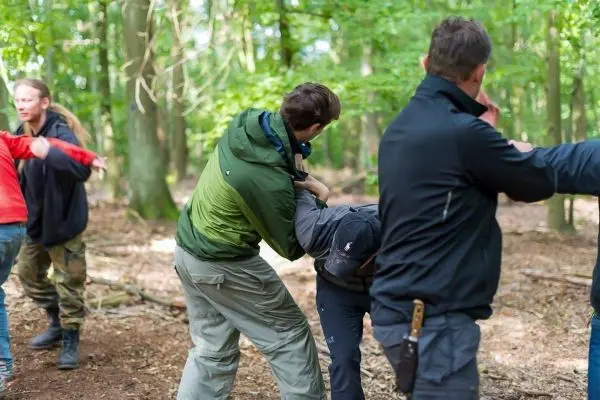 Person hilft anderer Person in einem Waldgebiet beim Training