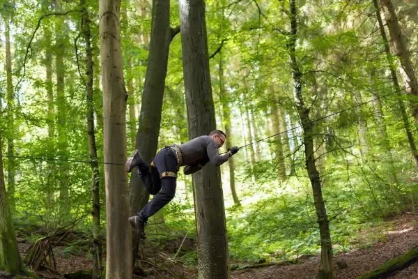 Person schwingt an Seil zwischen Bäumen im Wald
