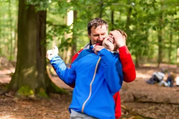 Person umarmt lachende Person im Wald