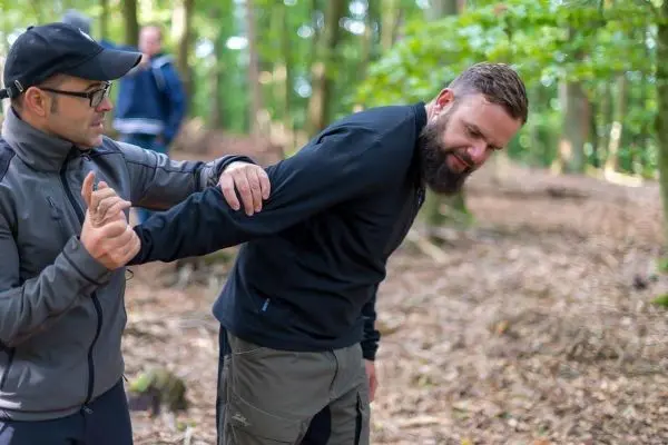 Person zeigt einer anderen Person eine Technik im Wald