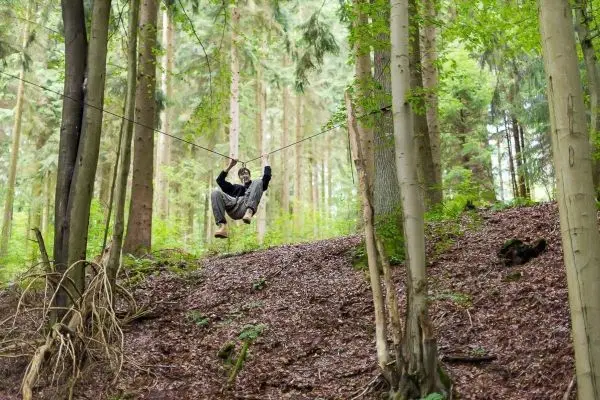 Selbstgebaute Seilquerung zwischen Bäumen wird überquert