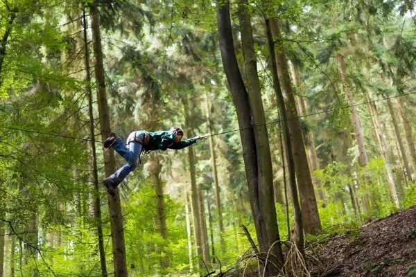 Selbstgebaute Seilquerung zwischen Bäumen wird von einer Person überquert
