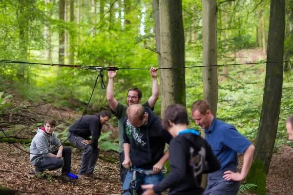 Teilnehmer bauten eine selbstgebaute Seilbrücke zwischen zwei Bäumen auf