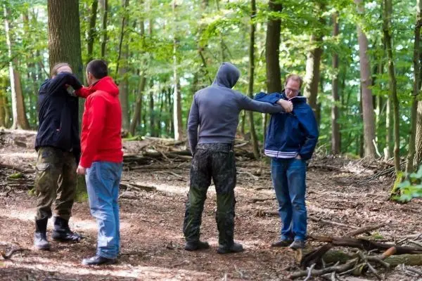 Vier Personen üben Techniken zur Selbstverteidigung im Wald