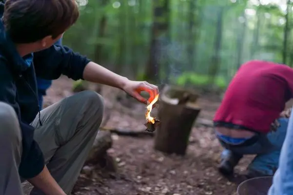 Zunder glimmt in der Hand, während Rauch aufsteigt