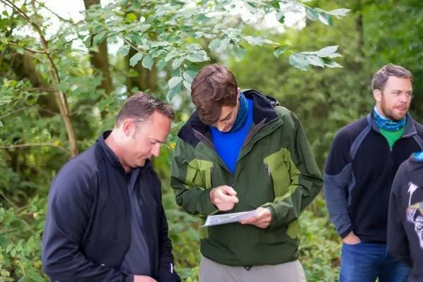 Zwei Personen betrachten eine Karte, während eine dritte Person im Hintergrund steht