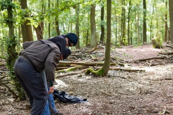 Zwei Personen beugen sich über einen Gegenstand auf dem Waldboden
