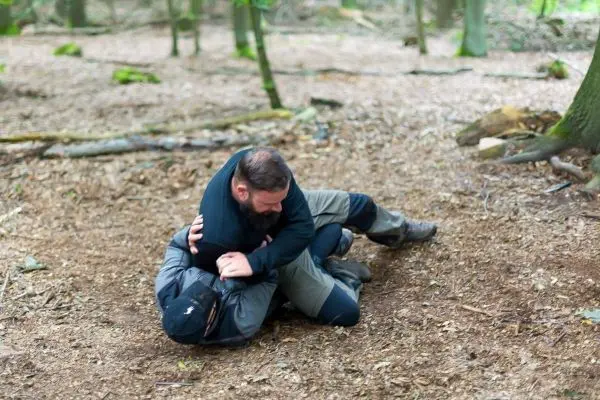 Zwei Personen kämpfen am Boden im Wald