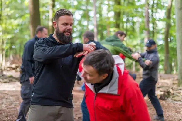 Zwei Personen üben eine Selbstverteidigungstechnik im Wald