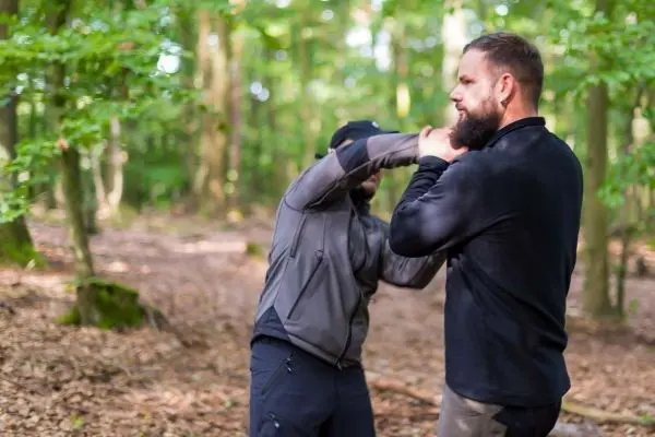 Zwei Personen üben eine Selbstverteidigungstechnik im Wald