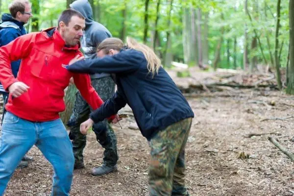 Zwei Personen üben eine Selbstverteidigungstechnik im Wald