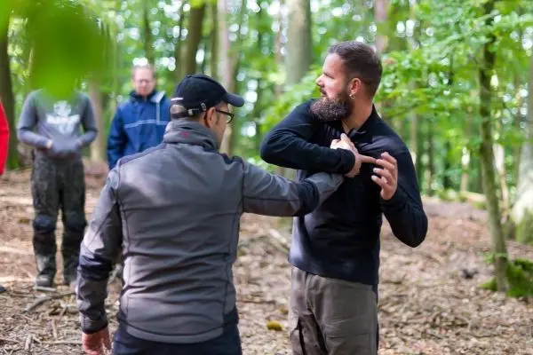 Zwei Personen üben eine Selbstverteidigungstechnik im Wald