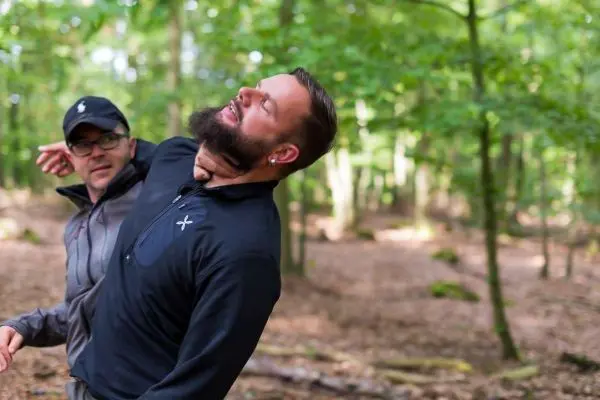 Zwei Personen üben eine Selbstverteidigungstechnik im Wald aus