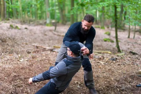 Zwei Personen üben eine Selbstverteidigungstechnik im Wald aus