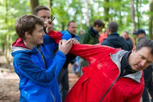 Zwei Personen üben eine Technik zur Armkontrolle im Wald aus